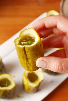 a person is holding an appetizer on a plate with other food items in the background