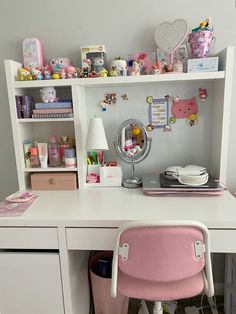 a white desk topped with a pink chair next to a shelf filled with lots of stuff