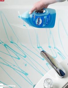 a person is using a hand sanitizer to clean a bathtub with blue paint