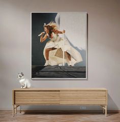 a white cat sitting on top of a wooden bench in front of a painting of a woman