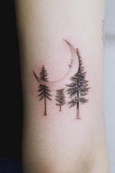 a tattoo with trees and a crescent on the side of the arm, which is black and white