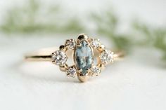 a close up of a gold ring with an oval shaped blue stone surrounded by small white diamonds