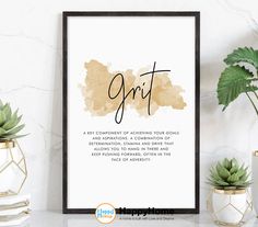 a framed print with the words spirit in black and gold on it, next to potted plants