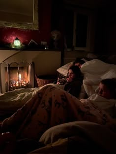 two people are laying in bed next to a fire place