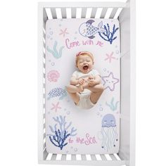 a baby in a white crib with an ocean theme on it's back