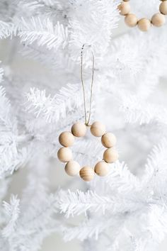 a white christmas tree with wooden beads hanging from it