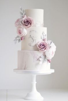 a white and pink wedding cake with flowers on top