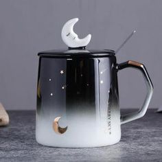 a black and white coffee pot with a crescent moon on it's lid sitting on a table