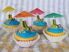 cupcakes with blue frosting and colorful decorations on top are sitting on a table