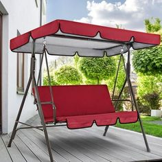 a red and white swing chair sitting on top of a wooden deck next to a house