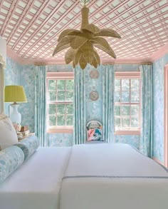 a bedroom with blue and white wallpaper and ceiling fan