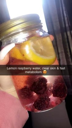 a person holding a mason jar filled with lemon, raspberry water, clear skin & fast