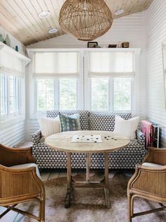 a living room with couches, chairs and a round table in front of two windows