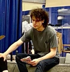 a man sitting on top of a couch next to a drum