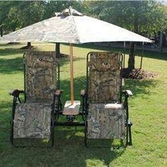 two lawn chairs sitting under an umbrella in the middle of a yard with grass and trees