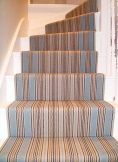 a cat sitting on top of a carpeted stair case next to a set of stairs