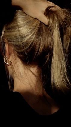 a woman with her hair in a ponytail is shown from the neck down, wearing gold hoop earrings