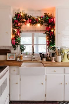 a kitchen decorated for christmas with wreaths and lights