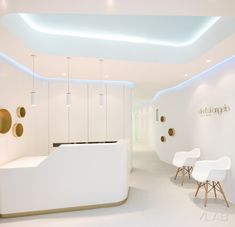 a white reception area with gold accents and round lights on the ceiling, along with two chairs