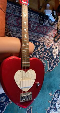 a red guitar sitting on top of a blue rug