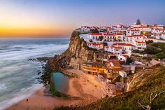 an aerial view of a beach with houses on the cliff