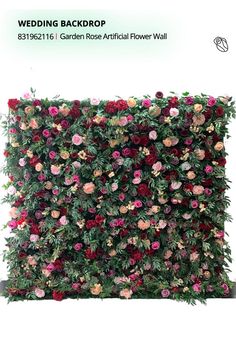 an artificial flower wall is shown with pink and red flowers on the top, along with green foliage