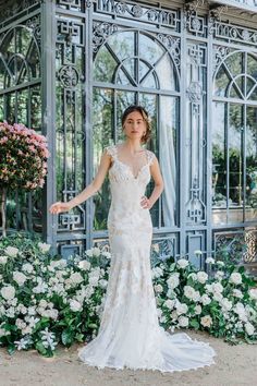 a woman standing in front of a building wearing a wedding dress and holding her arms out