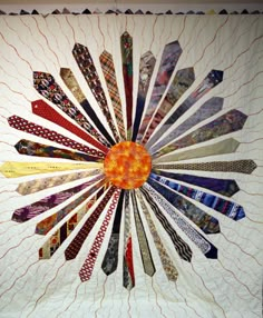 a quilted wall hanging with many different ties on it's center piece, in the shape of a sunburst