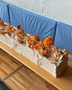 a cake with flowers on it sitting on a wooden table next to a blue bench