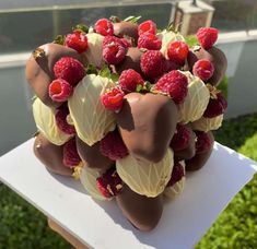 chocolate covered strawberries and raspberries are arranged on a white platter outside