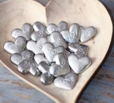 a heart shaped bowl filled with silver hearts and love words on it's sides