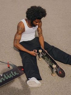 a man sitting on the ground with his skateboard