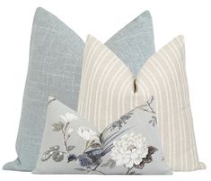 two decorative pillows sitting next to each other on a white surface with blue and grey stripes