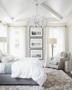 a bedroom with white furniture and pictures on the wall above the bed, along with a chandelier