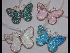 four different colored glitter butterfly ornaments on a white table