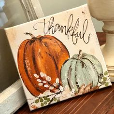 a painted sign that says, thank you and two pumpkins on the table next to it