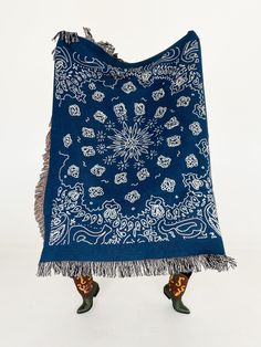 a blue and white blanket with an intricate design on the front, fringed edge