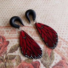 two pairs of red and black earrings on a floral tablecloth with polka dot dots