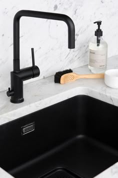 a kitchen sink with a black faucet and soap dispenser next to it