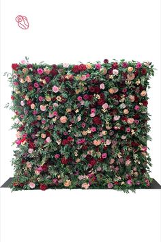 an artificial flower wall with pink and red flowers on it's sides, in front of a white background