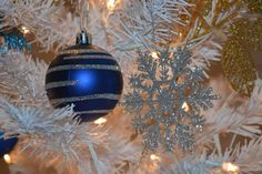 a blue and silver christmas ornament hanging from a white christmas tree