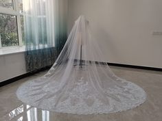 a white wedding veil sitting on top of a floor in front of a large window