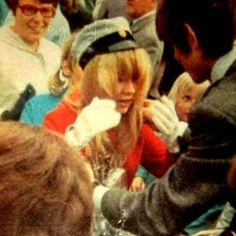 an old photo of some people sitting in a crowd and one is talking to someone on the phone