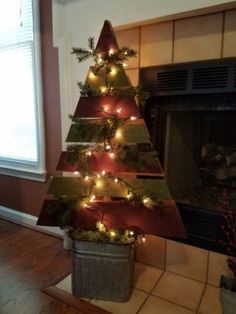 a christmas tree made out of tin cans with lights on it in front of a fireplace