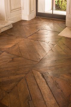 a wooden floor in front of a door with an open glass window on the other side