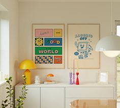 two posters are hanging on the wall above a white cabinet in a room with yellow accents