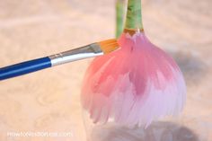 a close up of a paintbrush in a glass vase with pink and white feathers