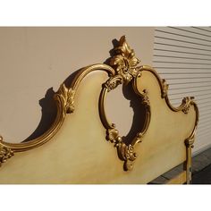 an ornate gold bed frame against a white wall