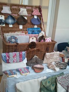 a table topped with lots of different types of cloths and bags next to a wicker basket