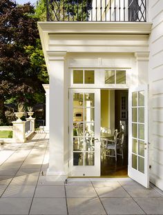 an open door to a white building with glass doors and railings on the outside